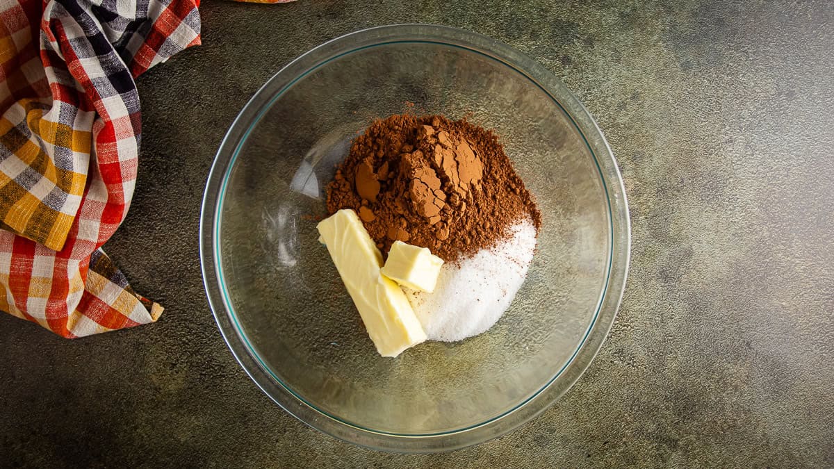 Sugar, butter, and cocoa in a glass bowl before being mixed