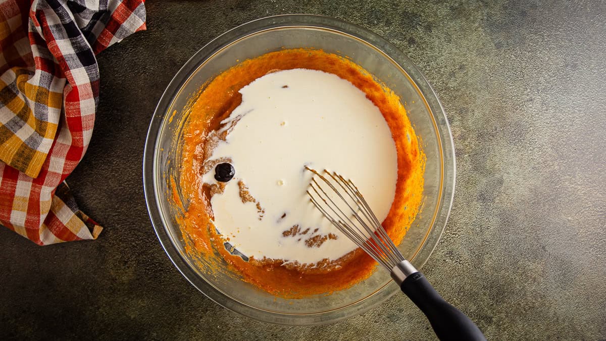 Adding cream and vanilla bean paste to pumpkin pie mix