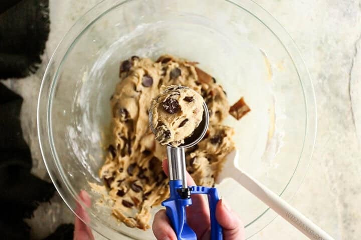Using a cookie scoop to portion dough for brown butter toffee chocolate chip cookies