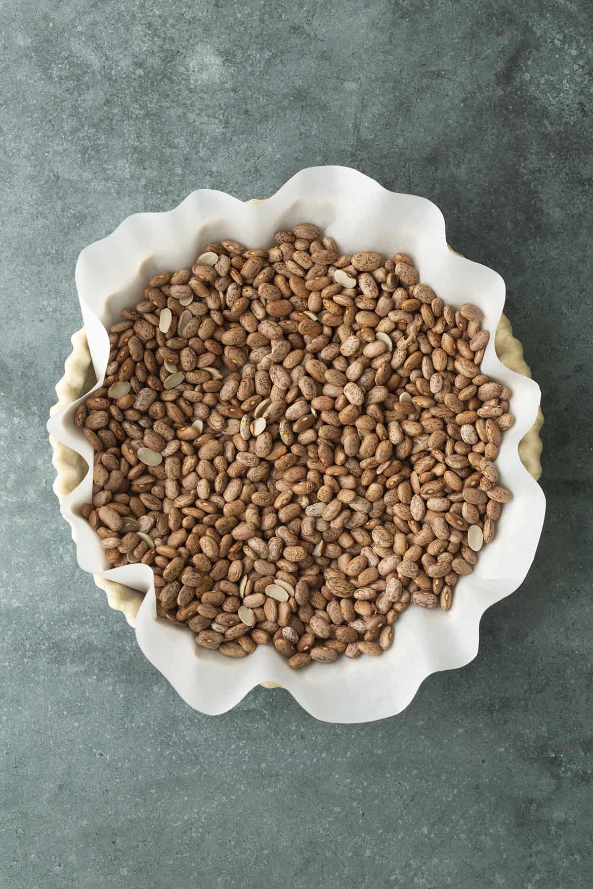 Beans in parchment paper over top of unbaked pie dough