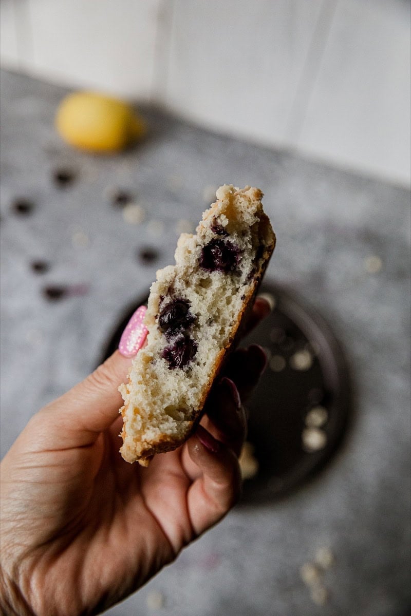 Close-up of blueberry muffin top with streusel topping held in hand.