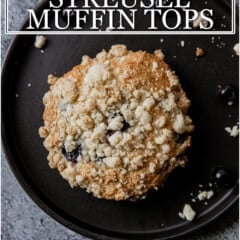 Close-up of a blueberry streusel muffin top on a black plate with crumb topping.