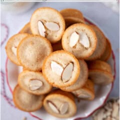 Stack of almond cookies with sliced almonds on top, on a white plate.