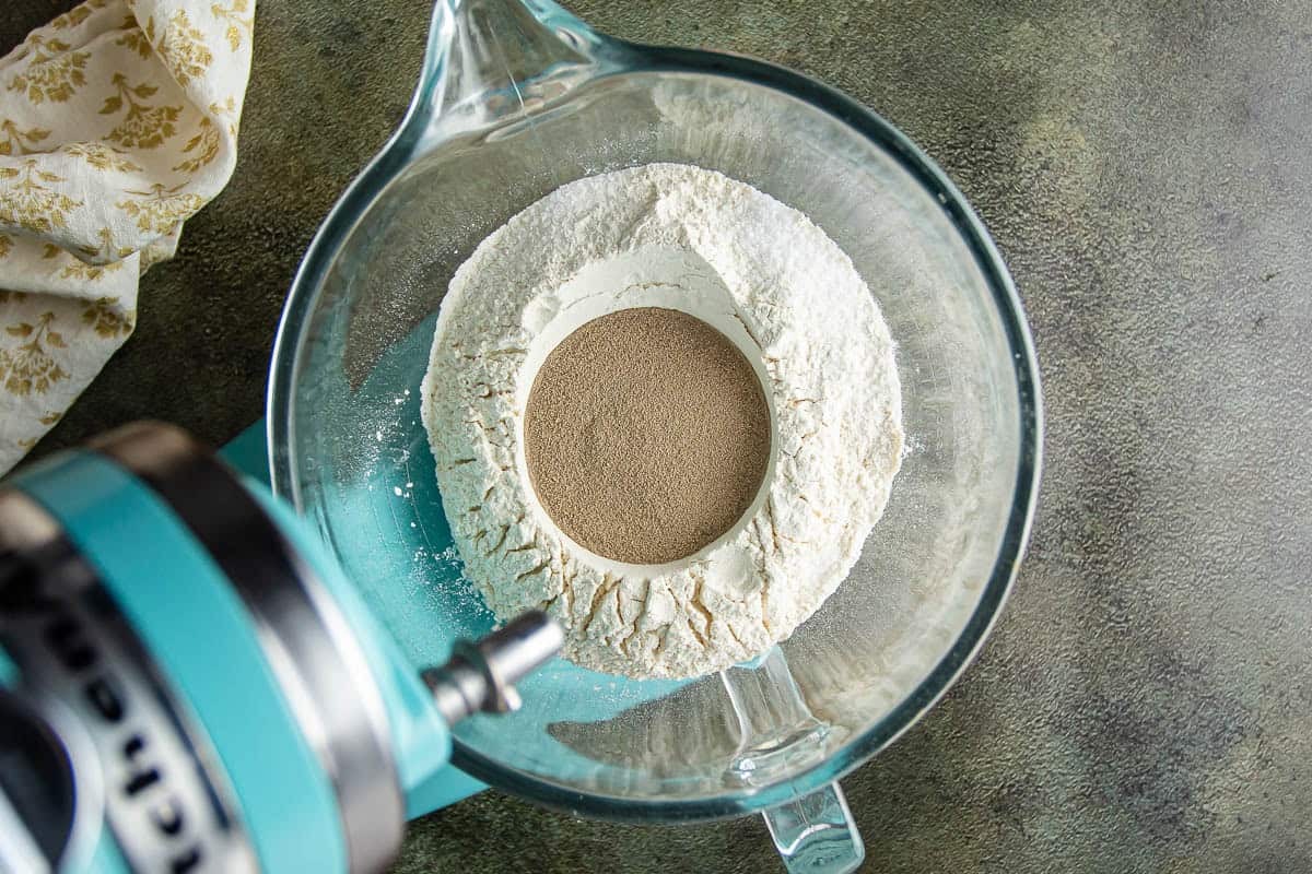 Flour and yeast in a glass mixing bowl for baking Parker House Rolls.