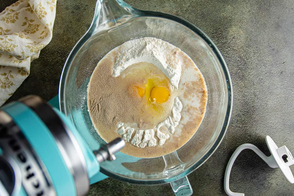 Mixing flour and egg in a glass bowl for baking Parker House Rolls.