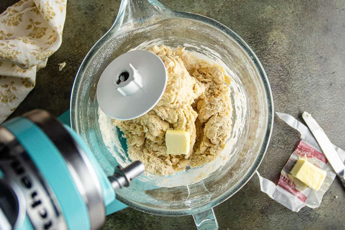 Mixing dough for Parker House Rolls in a glass bowl with butter and mixer.