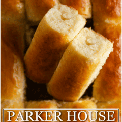 Close-up of freshly baked Parker House rolls with one cut open to show soft interior.