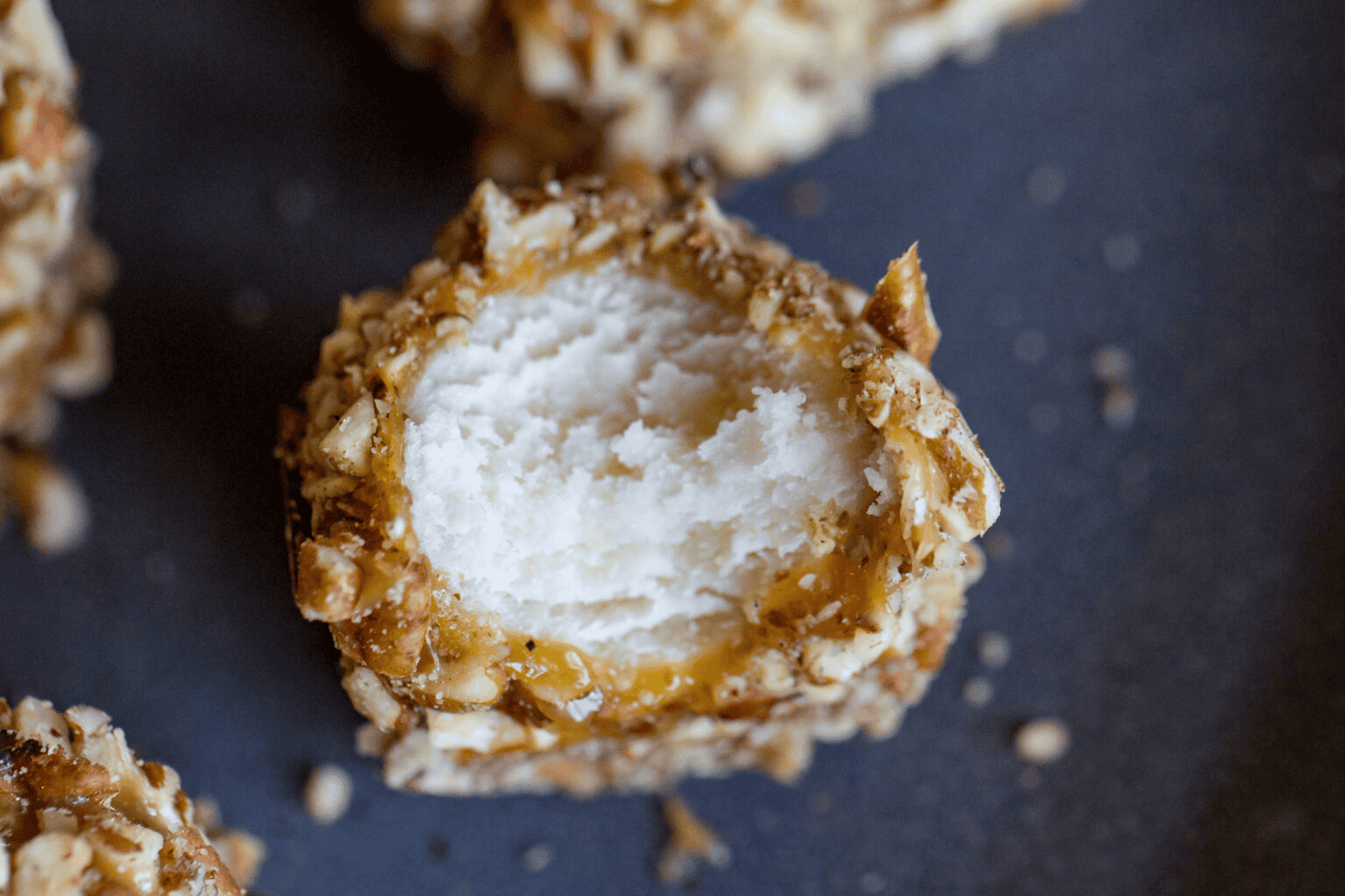 Close-up of a caramel-coated coconut truffle with a creamy center.